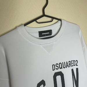 May include: White sweatshirt with a black 'DSQUARED2 ICON' graphic print. The sweatshirt has a crew neck and long sleeves. The size tag is visible and says 'DSQUARED2 L'.