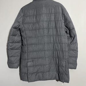 May include: A dark gray quilted puffer jacket with a stand-up collar.