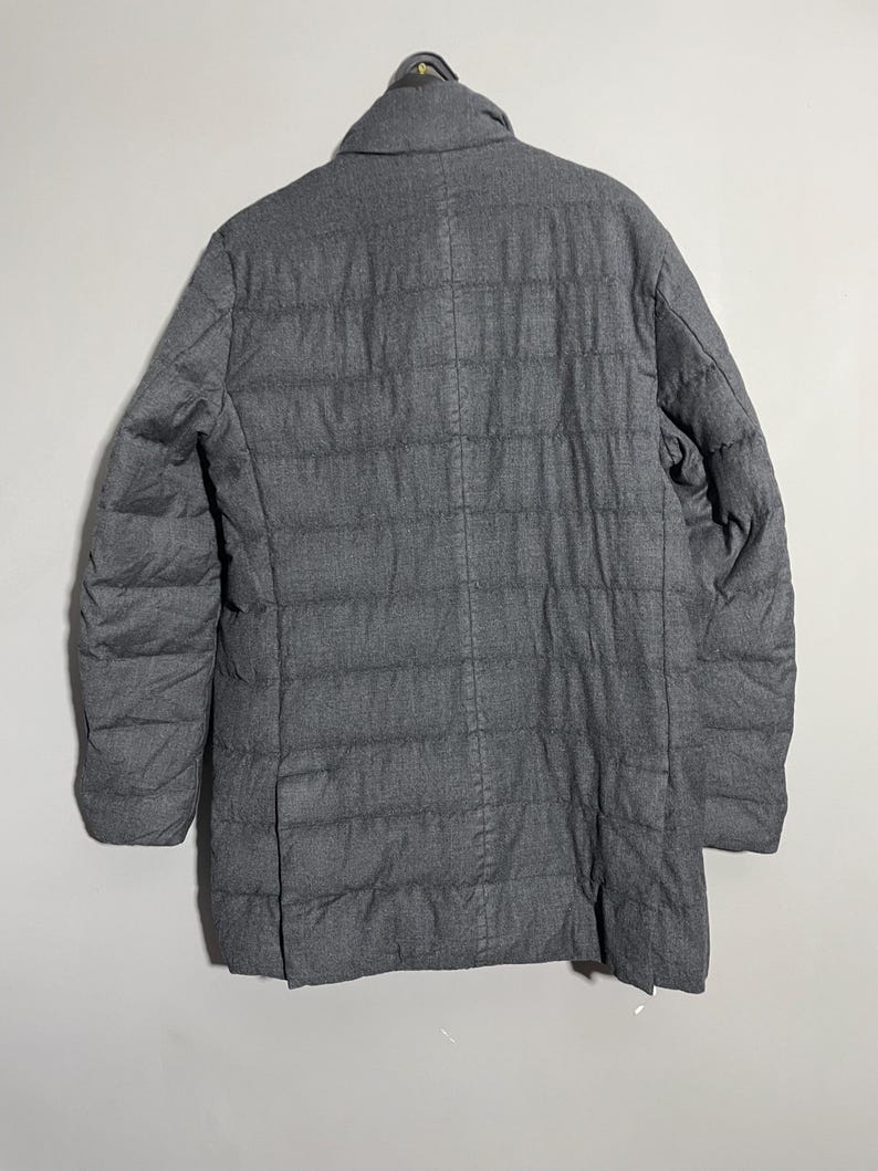 May include: A dark gray quilted puffer jacket with a stand-up collar.
