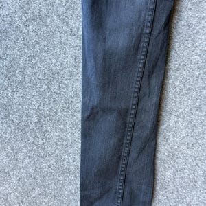 Op de afbeelding: Een donker antracietgrijze spijkerbroek met een klassieke vijf-pocket constructie, voorzien van zichtbare ton-sur-ton stiksels langs de zijnaden en een recht model, waarbij de textuur van de katoenen stof duidelijk zichtbaar is.