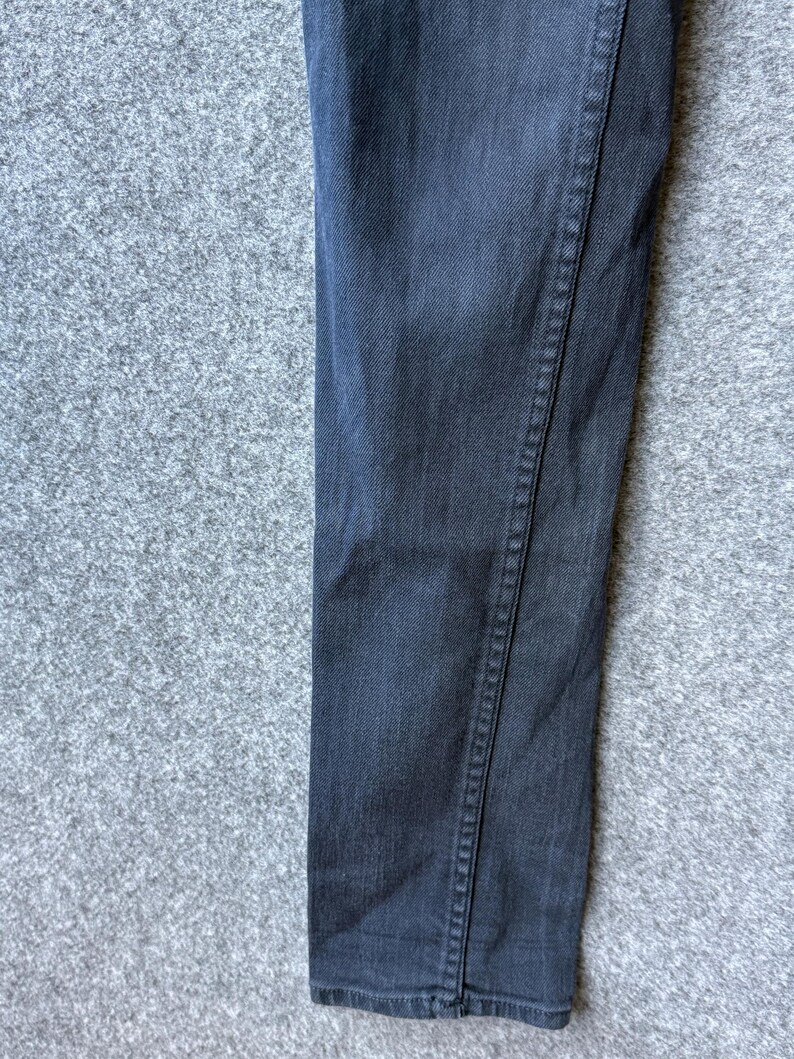 Op de afbeelding: Een donker antracietgrijze spijkerbroek met een klassieke vijf-pocket constructie, voorzien van zichtbare ton-sur-ton stiksels langs de zijnaden en een recht model, waarbij de textuur van de katoenen stof duidelijk zichtbaar is.