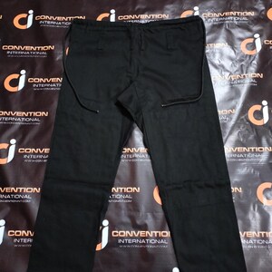May include: Black pants with a drawstring waist and straight leg design. The pants have a simple, classic style, suitable for various occasions. The fabric appears to be a durable material.