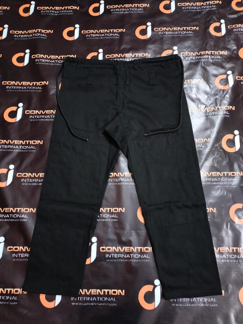 May include: Black pants with a drawstring waist and straight leg design. The pants have a simple, classic style, suitable for various occasions. The fabric appears to be a durable material.
