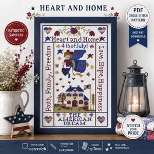 May include: A framed cross-stitch sampler with a patriotic theme. The design includes the text "Heart and Home," "4th of July," and "The American Dream." The sampler features a house, an angel, stars, and hearts in red, white, and blue.