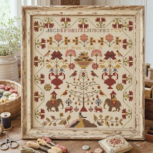 May include: A framed cross-stitch sampler on cream fabric featuring an alphabet, the text Margaret Price Aged 18 1857, floral motifs, birds, a central fruit bowl, and two elephants with riders, all rendered in muted red, green, and gold thread.