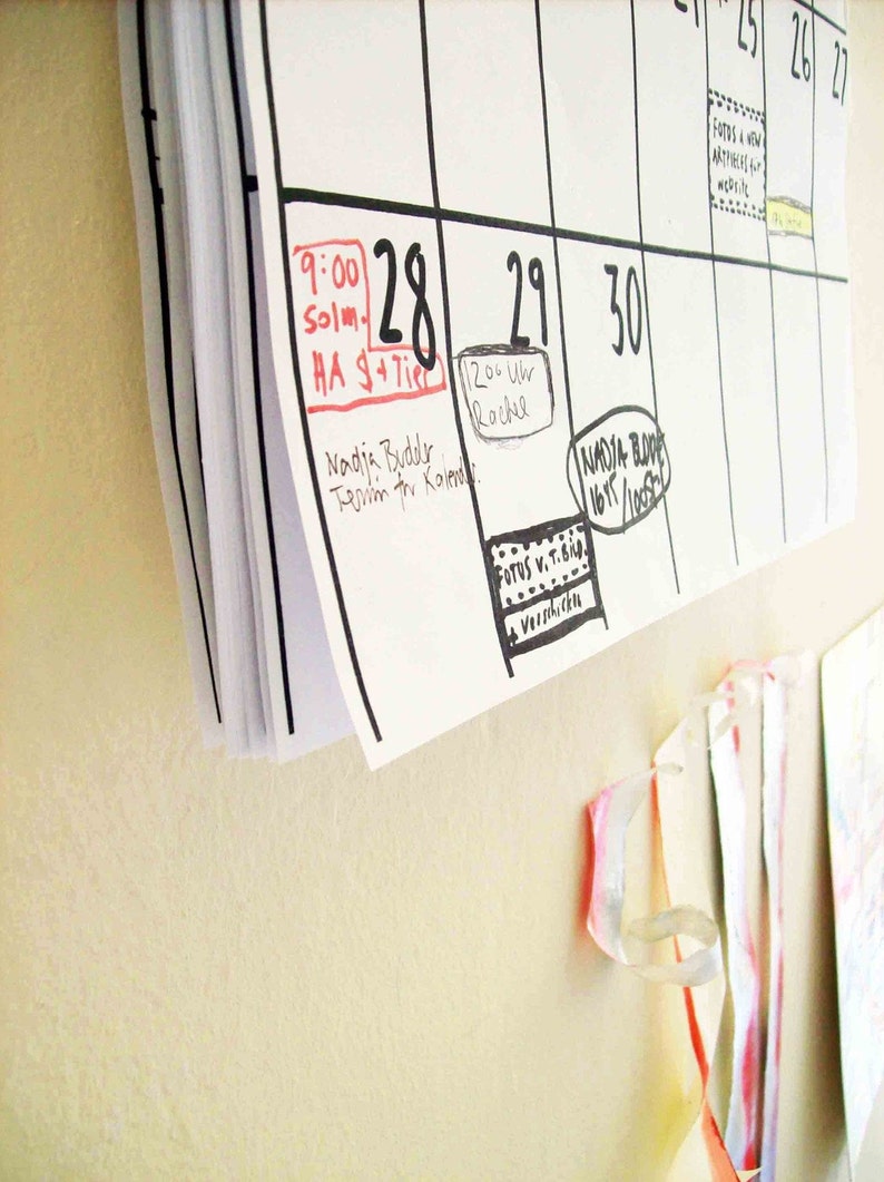 May include: A white calendar with black grid lines and handwritten appointments. The dates 28, 29, and 30 are circled in black marker. The date 28 has a red rectangle around it with the text "9:00 Solm. HA $+Tire" written inside. The date 29 has a circle around it with the text "12:00 Uhr Rachel" written inside. The date 30 has a circle around it with the text "NADJA BODE 16/1/1005" written inside.