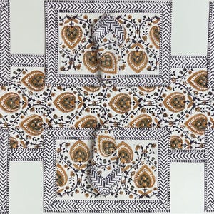 Puede incluir: Un camino de mesa y seis manteles individuales a juego con servilletas, todos con fondo blanco, un patrón floral de cachemira repetitivo en marrón y negro y un borde de chevrón en blanco y negro en los bordes de cada pieza textil.