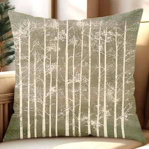 May include: Square decorative pillow with a forest design. The pillow features a pattern of white birch trees against a muted green background. The trees are vertically aligned, creating a natural, outdoorsy theme.