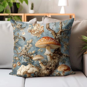 May include: Square throw pillow with a whimsical mushroom design. The pillow features a light blue background with detailed illustrations of various mushrooms, branches, and floral elements. The largest mushroom has a red and white spotted cap.