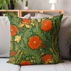 May include: A square decorative pillow with a floral pattern. The design features large orange flowers and golden leaves against a dark green background. The pillow is placed on a light-colored sofa.