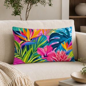 May include: A rectangular throw pillow featuring a vibrant tropical print with large pink hibiscus flowers, orange bird of paradise blooms, and various green palm and monstera leaves set against a deep navy blue background.