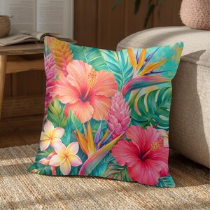 May include: A square throw pillow featuring a vibrant tropical print with large peach and pink hibiscus flowers, yellow plumeria blossoms, orange bird of paradise flowers, and various green palm leaves set against a bright teal background.