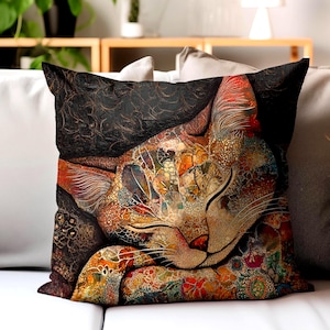 May include: A decorative square pillow featuring a colorful, artistic rendering of a sleeping cat. The cat's fur is a mosaic of warm colors, including orange, red, and gold, set against a dark, patterned background. The pillow is on a white surface.