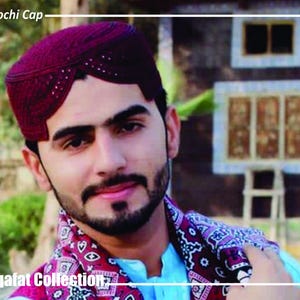 Peut inclure: Un bonnet Balochi marron avec un motif décoratif. Le bonnet est porté par une personne portant une écharpe à motifs et une chemise bleue. Le texte "Balochi Cap" et "Saqafat Collection" sont visibles.