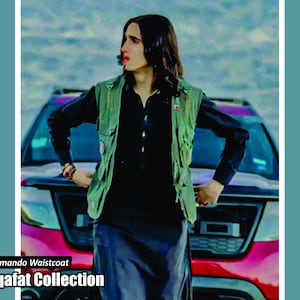 May include: A person wearing a green commando waistcoat over a black shirt and dark blue pants. The image includes the text "Commando Waistcoat" and "Saqafat Collection". The background features a red car and a body of water.