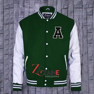 Könnte beinhalten: Grün-weiße Collegejacke mit dem Buchstaben "A" auf der Brust. Die Jacke hat weiße Ärmel, einen grünen Körper und weiß-grüne Streifen am Kragen, an den Manschetten und am Saum. Die Jacke hat eine Knopfleiste und den Text "Zaine Enterprises" ist sichtbar.