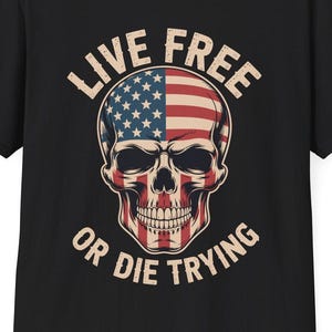 May include: Black t-shirt featuring a skull design with the American flag incorporated into the skull's features. The text "LIVE FREE" arches above the skull, and "OR DIE TRYING" curves below.