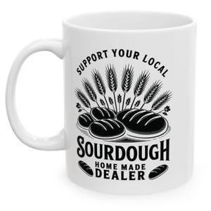 May include: White ceramic mug with a black graphic design. The design features wheat stalks, loaves of bread, and the text "SUPPORT YOUR LOCAL SOURDOUGH HOME MADE DEALER."