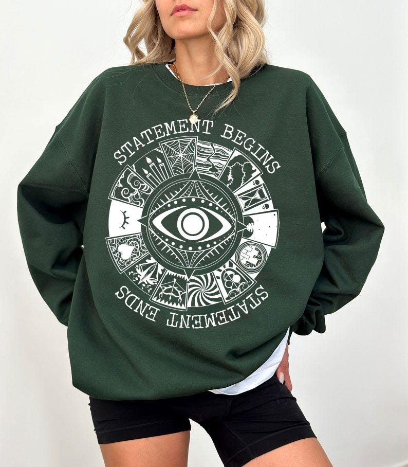 Puede incluir: Sudadera verde oscuro con un dise&ntilde;o gr&aacute;fico blanco que presenta un ojo, im&aacute;genes de tarot y el texto "STATEMENT BEGINS STATEMENT ENDS". La sudadera tiene mangas largas y cuello redondo.
