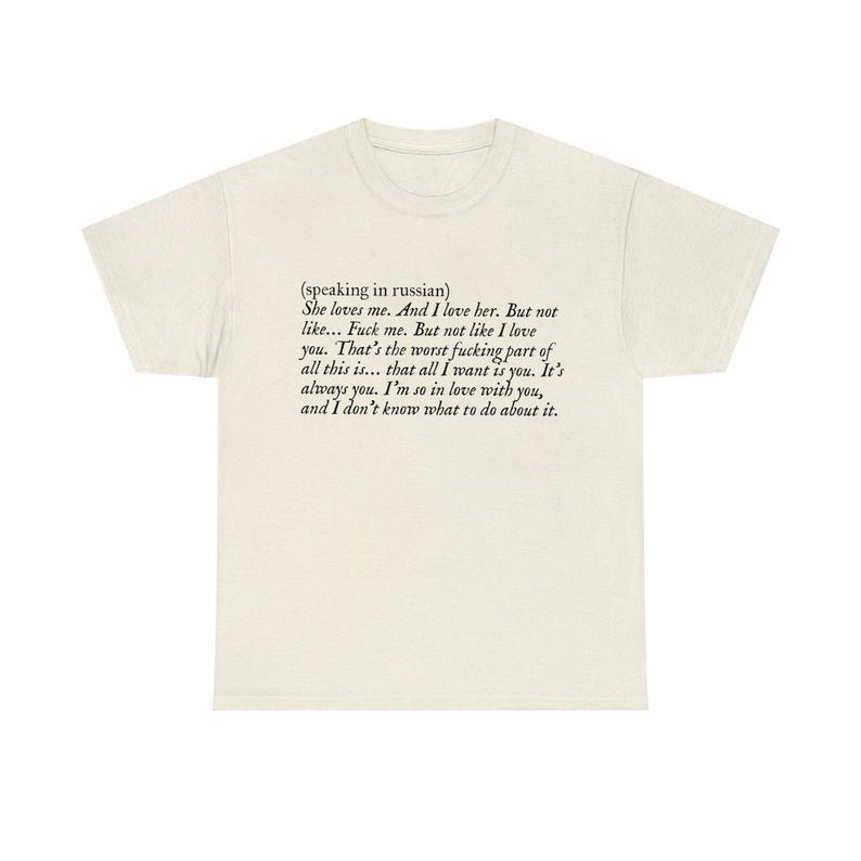 May include: Cream-colored t-shirt with black text. The text includes the phrase "She loves me. And I love her. But not like... Fuck me. But not like I love you." The shirt has a crew neck and short sleeves.