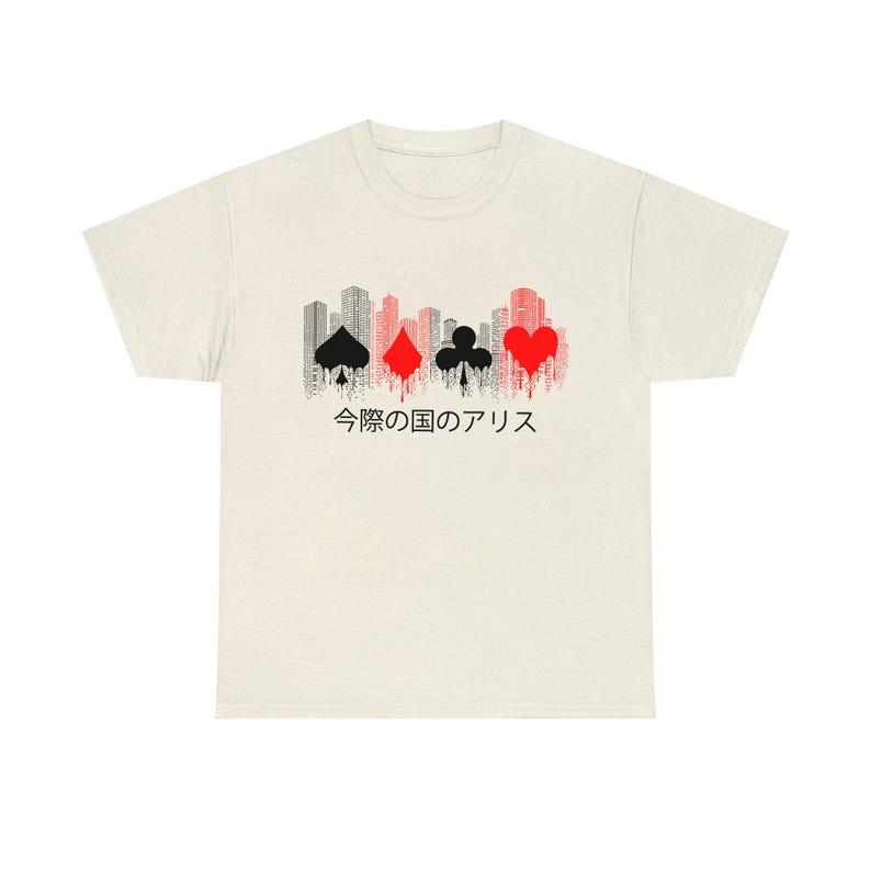 Puede incluir: Camiseta color crema con un dise&ntilde;o gr&aacute;fico que presenta los palos de las cartas y una silueta de paisaje urbano. El dise&ntilde;o incluye picas negras, diamantes rojos, tr&eacute;boles negros y un coraz&oacute;n rojo, con texto japon&eacute;s debajo.