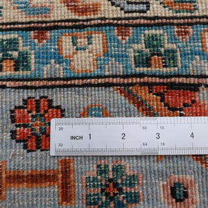 May include: Close-up of a blue and white rug with a floral pattern. A ruler is placed on the rug, showing a measurement of 5 inches.