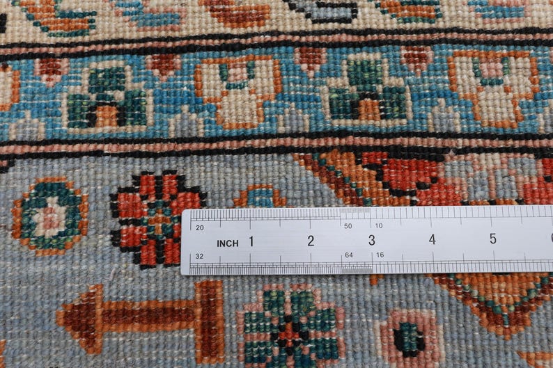 May include: Close-up of a blue and white rug with a floral pattern. A ruler is placed on the rug, showing a measurement of 5 inches.