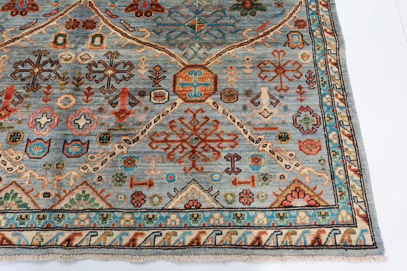May include: A blue rug with a geometric pattern in shades of red, orange, and white. The rug has a fringe border.