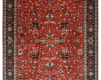 May include: A rectangular area rug with an intricate, traditional design. The rug features a rich red central field with a detailed pattern of floral and geometric motifs in shades of blue, beige, and green. A dark blue border frames the design.