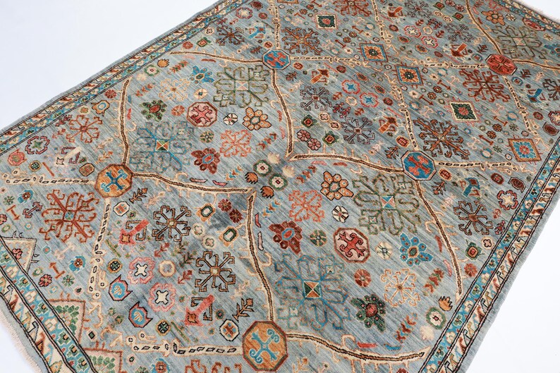 May include: A blue rug with a geometric pattern in shades of red, orange, green, and blue. The rug has a border with a repeating pattern.