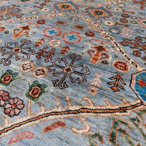 May include: A blue rug with a traditional Persian design featuring intricate patterns of flowers, stars, and geometric shapes in shades of red, orange, green, and brown.
