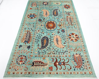 May include: A teal blue rug with a floral pattern. The rug has a central medallion with a paisley design and a border with a repeating pattern of flowers and leaves.