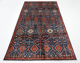 May include: A blue and red rug with a geometric pattern. The rug has a diamond pattern with floral motifs in the center of each diamond. The rug has a border with a repeating pattern.