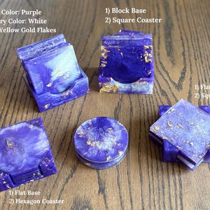 May include: A collection of purple and white resin coasters with yellow gold flakes. The set includes square and hexagonal coasters paired with matching block or flat bases. Text labels identify the primary colour, secondary colour, and base types.