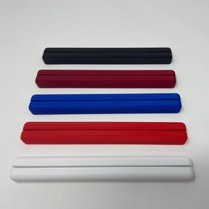 May include: Five different colored plastic phone stands. The stands are black, burgundy, blue, red, and white.