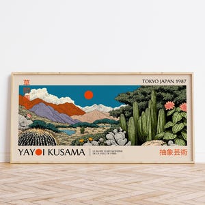 Puede incluir: Una impresión artística enmarcada que presenta un paisaje con montañas, cactus y un sol rojo contra un cielo azul. La impresión incluye el texto "YAYOI KUSAMA" y "TOKYO JAPAN 1987". La obra de arte tiene una estética vintage.