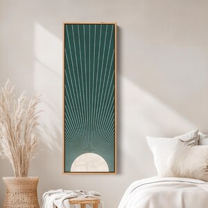 May include: A framed wall art piece featuring a geometric design. The artwork has a dark green background with white lines radiating from a cream-colored semi-circle at the bottom. The frame is made of light-colored wood. The artwork is rectangular and vertically oriented.