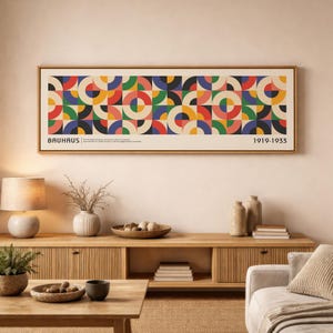 May include: A rectangular wall art print in a wooden frame featuring a repeating geometric pattern of circles and semicircles in red, yellow, green, blue, and black. The text BAUHAUS and 1919-1933 is printed in black on the bottom left and right.