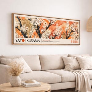 May include: A framed art print featuring a colorful abstract landscape with black tree branches and white blossoms against a background of orange and tan hues. The print includes the text "YAYOI KUSAMA" and Japanese text.