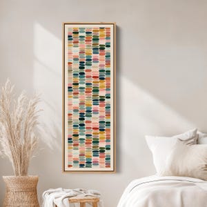 May include: A framed vertical abstract art piece featuring a pattern of colorful, oblong shapes. The shapes are arranged in vertical rows and include shades of pink, green, blue, yellow, and red. The artwork is encased in a light-colored wooden frame.