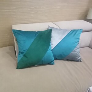 May include: Two decorative throw pillows with a geometric design. The pillows are made of a soft, plush fabric and feature a combination of teal, green, and gray colors.