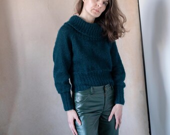 May include: A woman wearing a dark green fuzzy sweater and dark green leather pants.