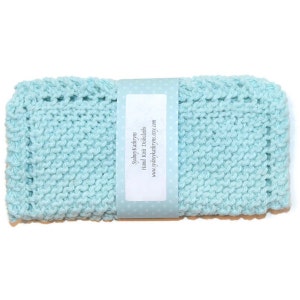 May include: A light blue knitted dishcloth with a white label that reads "SydneyKathryns Hand Knit Dishcloths www.sydneykathryns.etsy.com"