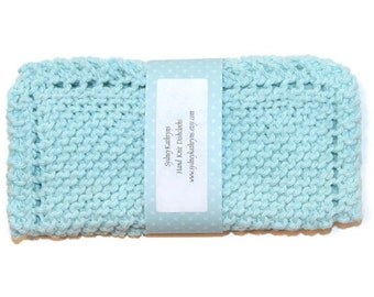 May include: A light blue knitted dishcloth with a white label that reads "SydneyKathryns Hand Knit Dishcloths www.sydneykathryns.etsy.com"