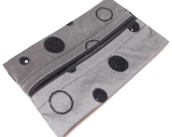 May include: A grey zipped pouch with a black polka dot pattern. The pouch is made of a soft, textured fabric.