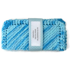 Könnte beinhalten: Ein handgestrickter Geschirrtuch in Blau und Türkis mit einem weißen Etikett, auf dem "SydneyKathryn's Hand Knit Dishcloths www.sydneykathryns.etsy.com" steht.