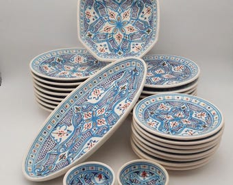 Może przedstawiać: Zestaw 18 ceramicznych talerzy w różnych rozmiarach i kształtach, z geometrycznym wzorem w kolorze niebieskim i białym z czerwonymi i zielonymi akcentami. Talerze są ozdobione kwiatowym wzorem.