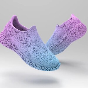 Puede incluir: Un par de zapatillas sin cordones en degradado azul y morado. Los zapatos tienen un dise&ntilde;o &uacute;nico de tejido abierto, creando una apariencia texturizada. Las zapatillas parecen flotar sobre un fondo blanco, mostrando su est&eacute;tica moderna.
