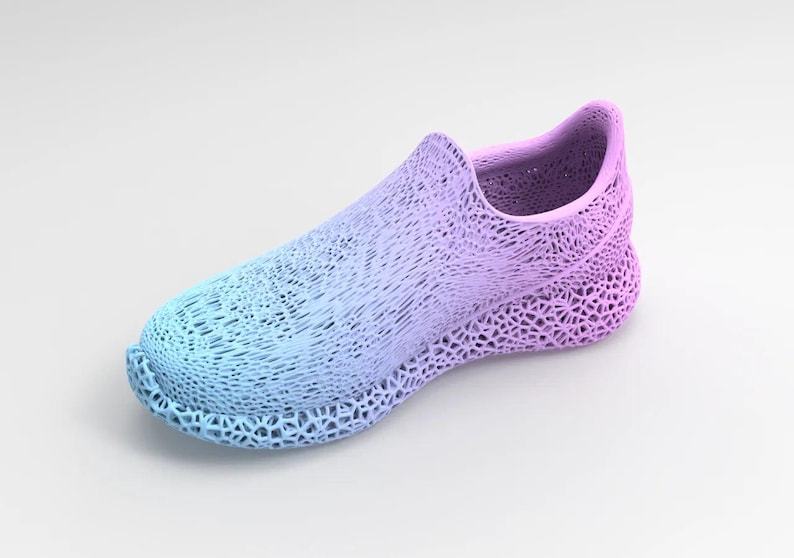 Puede incluir: Zapato renderizado digitalmente en degradado de azul y morado. El zapato tiene un dise&ntilde;o &uacute;nico de tejido abierto, con una apariencia texturizada. La suela y la parte superior est&aacute;n integradas, creando una est&eacute;tica moderna y sin costuras. Es un zapato sin cordones.