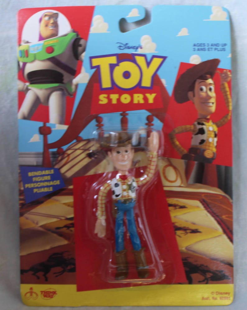 May include: A bendable Woody action figure from Toy Story in its original packaging. The card features Buzz Lightyear and Woody graphics, with the text Toy Story, Ages 3 and Up, and Bendable Figure. The figure wears a cowboy hat, vest, and boots.